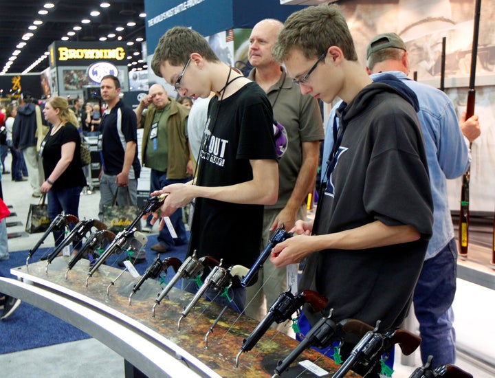 Gun enthusiasts look over Benelli USA guns at the National Rifle Association's (NRA) annual meetings & exhibits show in L