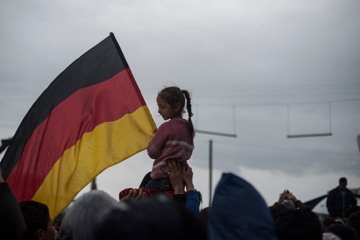 A child raises a German flag at a refugee camp.
