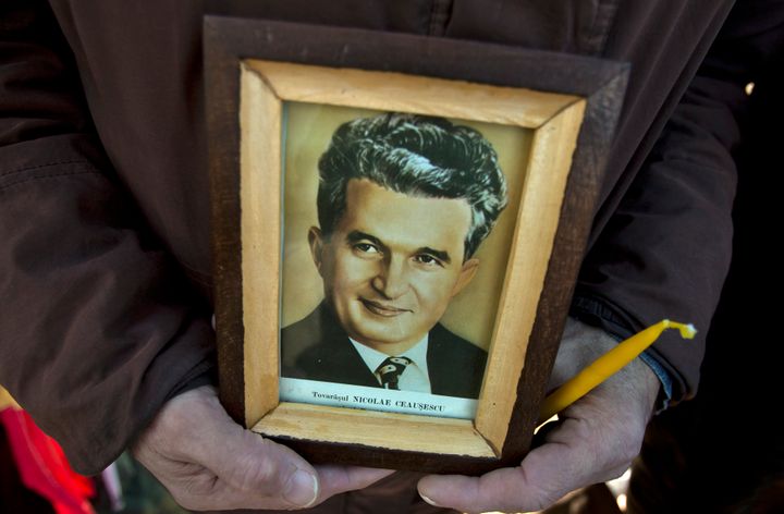 A man holds a framed picture of Romanian communist dictator Nicolae Ceausescu.