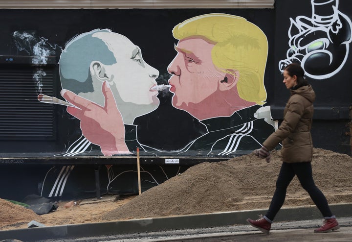 A woman walks past a mural showing President-elect Donald Trump (R) blowing marijuana smoke into the mouth of Russian President Vladimir Putin on the wall of a restaurant on Nov. 23, 2016, in Vilnius, Lithuania.