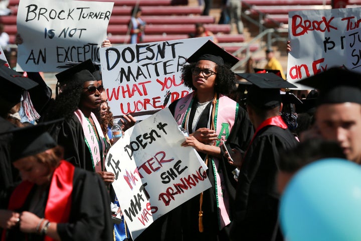 Protesters hold signs to raise awareness of sexual assault on campus at the Stanford University commencement ceremony in Palo
