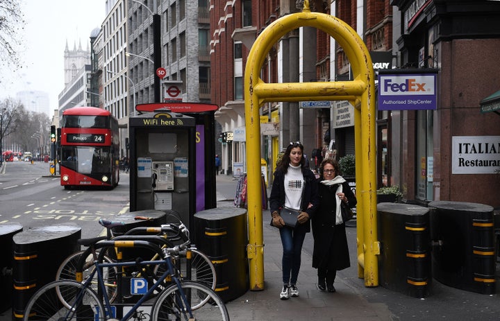 People walk through temporary security barriers placed on Victoria Street in central London, ahead of the New Year celebrations