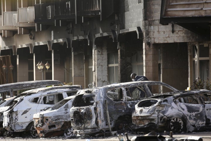 A gendarme inspects burnt-out vehicles outside the Splendid Hotel in Ouagadougou, Burkina Faso, on Jan. 16.