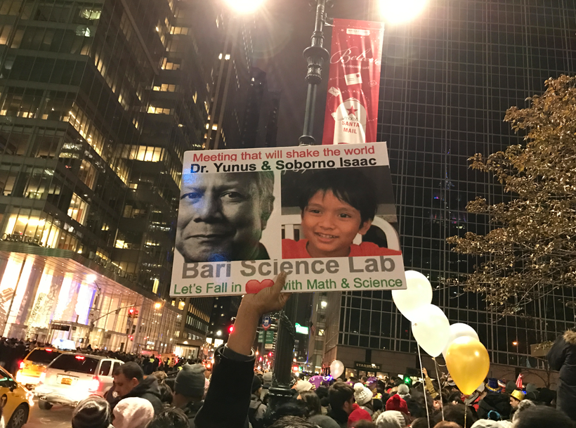 A fan of Isaac holds up poster at Times Square before New Year Celebration to promote the upcoming meeting between Nobel Laur