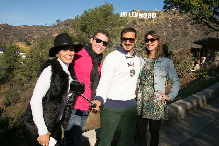 Tourists pose for a selfie in front of the 'Hollweed' sign.