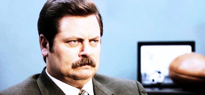 Parks and Recreation’s Ron Swanson(Nick Offerman) scowls uncomfortably. 