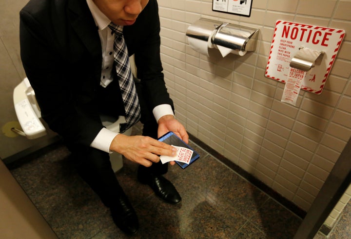 A man demonstrates the new cellphone toilet paper. 