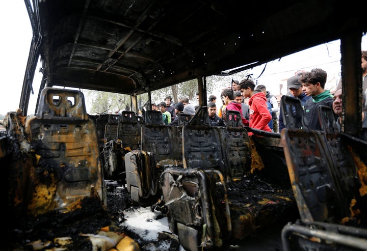People look at a burned vehicle at the site of car bomb attack in a busy square at Baghdad's sprawling Sadr City district, in