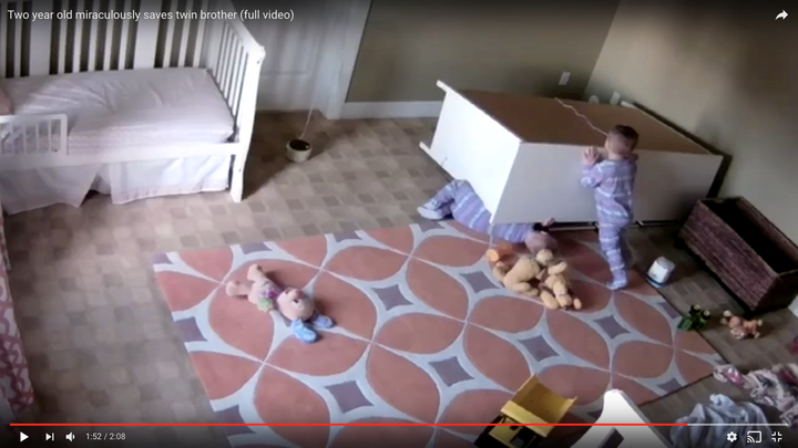 The 2-year-old boy is seen pushing a dresser off of his twin brother after it toppled on him in their bedroom last week.