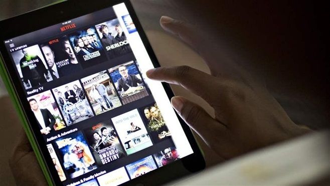 A customer selects videos on a Netflix app. With cities and states facing declining sales tax revenue, some are moving to tax audio and video streaming services, leaving consumers outraged.
