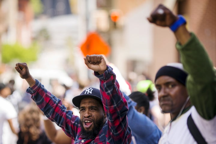 Pedestrians gesture as a march passes by on the way to a rally at Baltimore city hall in Baltimore, Maryland May 2, 2015. A jubilant Baltimore headed into a weekend of rallies after six police officers were criminally charged over the arrest of 25-year-old black man Freddie Gray whose death led to rioting earlier in the week. REUTERS/Lucas Jackson