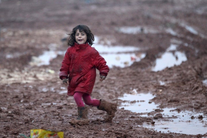 An internally displaced Syrian girl runs through mud in the Bab Al-Salam refugee camp, near the Syrian-Turkish border, northern Aleppo province, Syria December 26, 2016. REUTERS/Khalil Ashawi