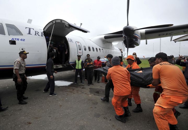 Rescue team members carry the body of one of the victims recovered from the crash site at Oksob village into Trigana Air airplane in Oksibil airport.