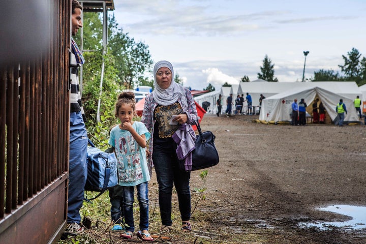 A refugee family waits on a gate inside a temporary tent camp on July 27, 2015 in Dresden, Germany.