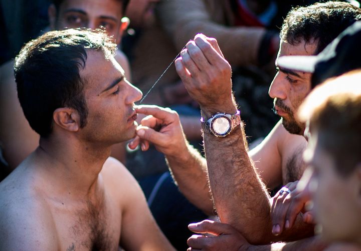 A man sews shut the mouth of a fellow migrant from Iran as migrants and refugees wait to cross the Greek-Macedonian border near Gevgelija on November 23, 2015.