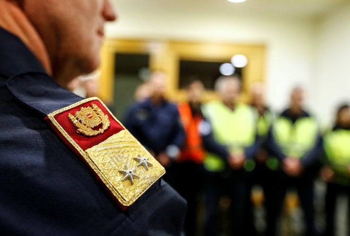 Police officers have a meeting before checking a freight train for migrants during a routine check on a train station in Stei