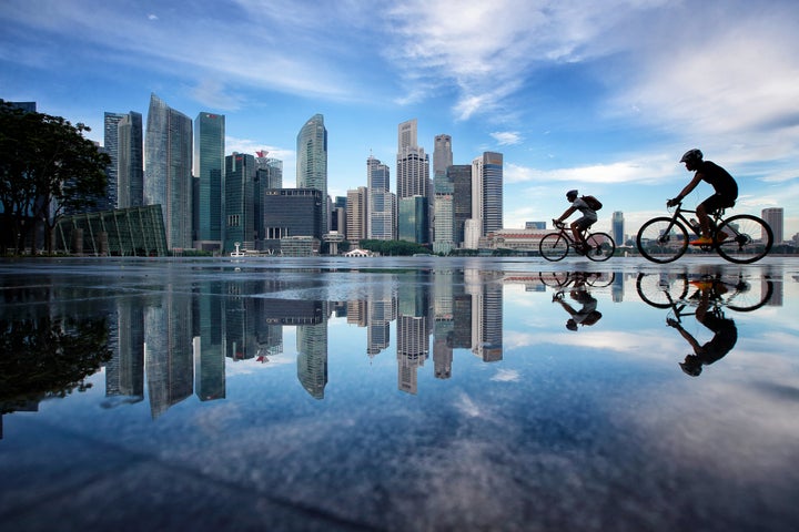 People cycle along Marina Bay with the Singapore Central Business District skyline in the background on November 2, 2016 in Singapore. The city has the world's highest cost of living.