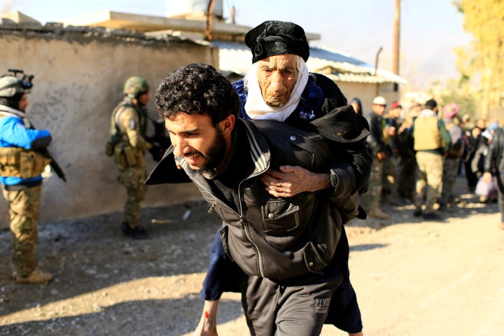 A displaced man, who fled the Islamic State stronghold of Mosul, carries a woman in the Mithaq district of eastern Mosul, Iraq, January 3, 2017.