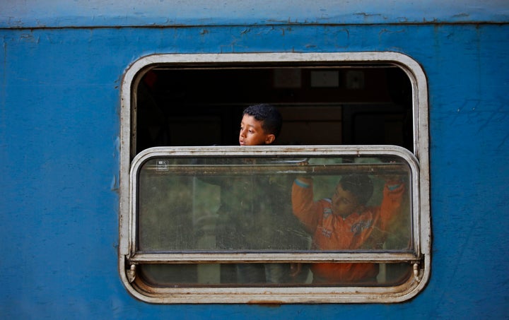 Children peer from a train window at the station in Roszke, Hungary September 15, 2015.