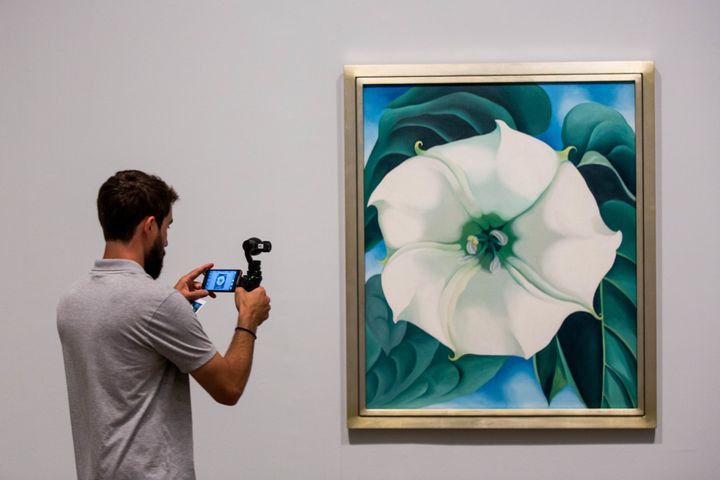 A photographer takes a photo of a painting by Georgia O'Keeffe.