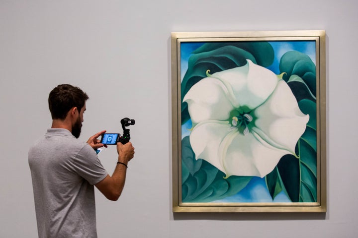 A photographer takes a photo of a painting by Georgia O'Keeffe.