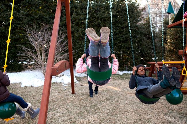 First Lady Michelle Obama and daughters, Malia and Sasha, play on their swing set in 2009.