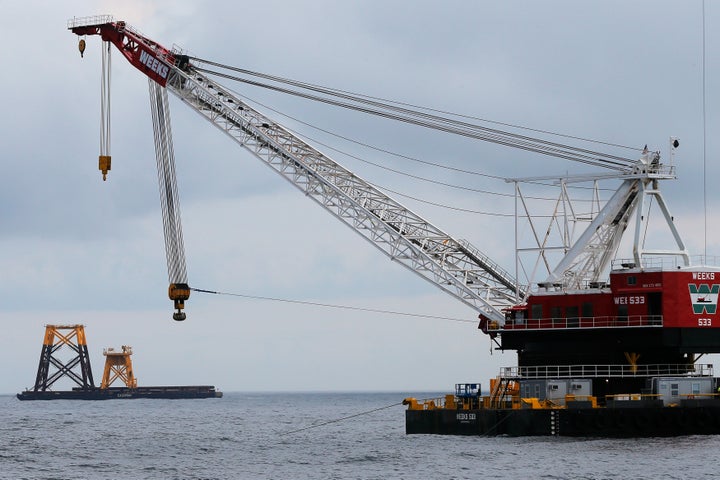 A construction crane floats next to a barge carrying jacket support structures and a platform for a turbine for a wind farm in the waters of the Atlantic Ocean off Block Island, Rhode Island July 27, 2015.