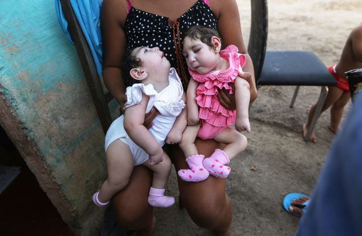 A family member holds twins Eloisa (L) and Eloa, both 8 months old and both born with microcephaly, during a Christmas gathering at the home of the twin's grandparents on December 25, 2016 in Areia, Paraiba state, Brazil. The mother of the twins Raquel said she contracted Zika during her pregnancy.