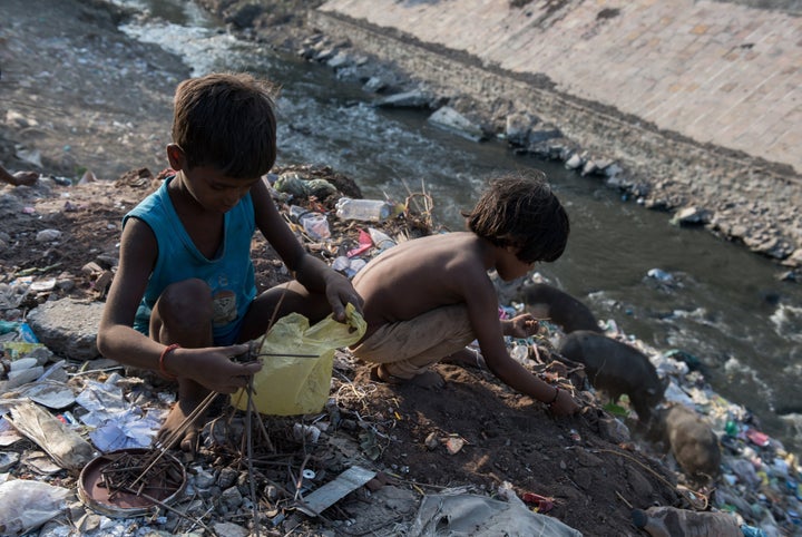 Indian boys sort through waste on the banks of a tributary flowing into the heavily polluted Ganges River. Varanasi, India. S