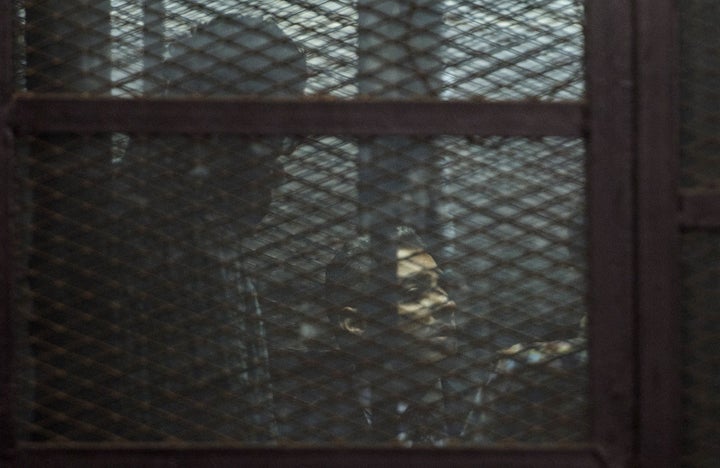 Al-Jazeera journalists, Canadian Mohamed Fahmy (C) and Egyptian Baher Mohamed (unseen), both accused of supporting the blacklisted Muslim Brotherhood in their coverage for the Qatari-owned broadcaster, sit in the defendants' cage during their trial in the capital Cairo on August 29, 2015.