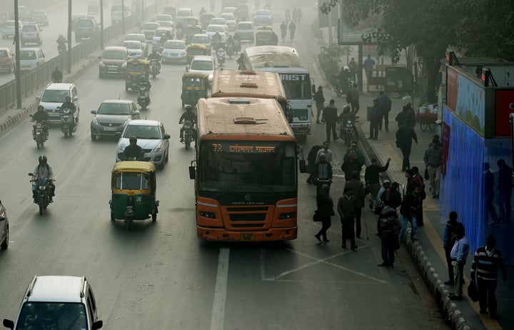 Indian commuters wait for their ride at a bus stop (R) where air purifiers have been installed in New Delhi on December 27, 2016.