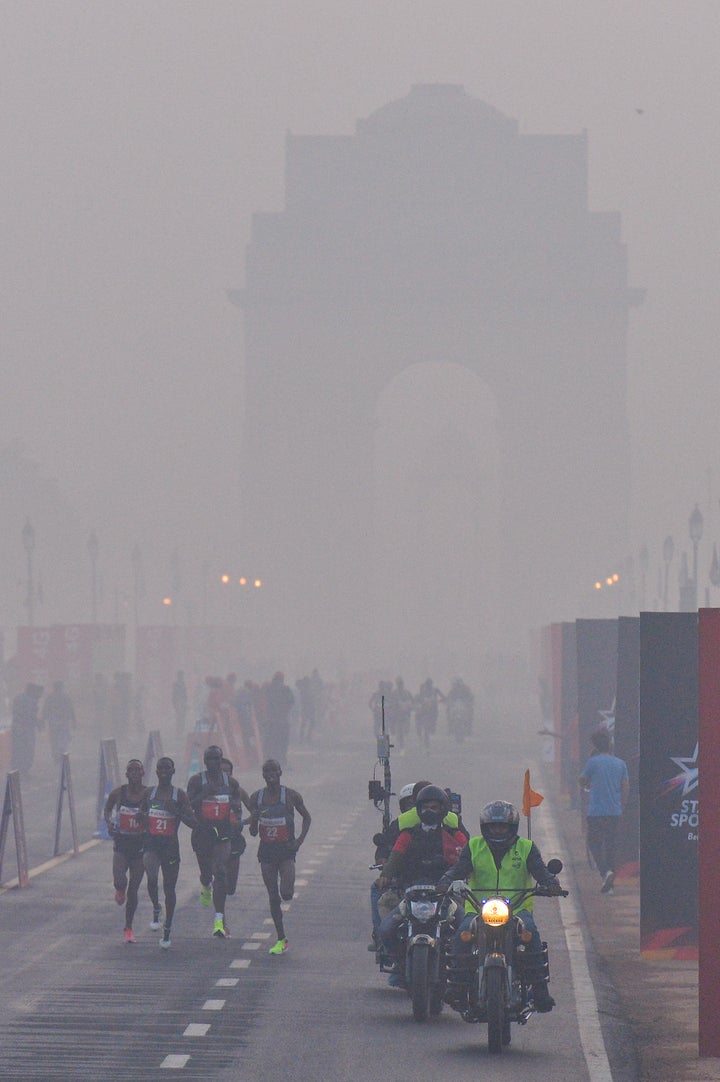 Participants run on Rajpath in front of India Gate, obscured by fog and smog, at the Delhi Half Marathon in New Delhi on November 20, 2016.