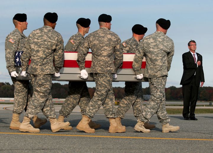 Secretary of Defense Ashton Carter stands at attention while an Army team transfers the remains of Master Sgt. Joshua L. Wheeler at Dover Air Force Base in Dover, Delaware. 