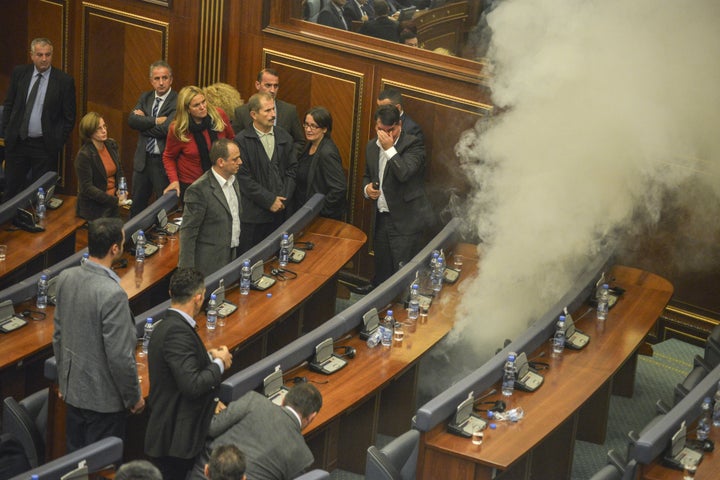 Kosovo parliamentary lawmakers step back as tear gar fills the chamber at Kosovo's parliament in Pristina on October 23, 2015.