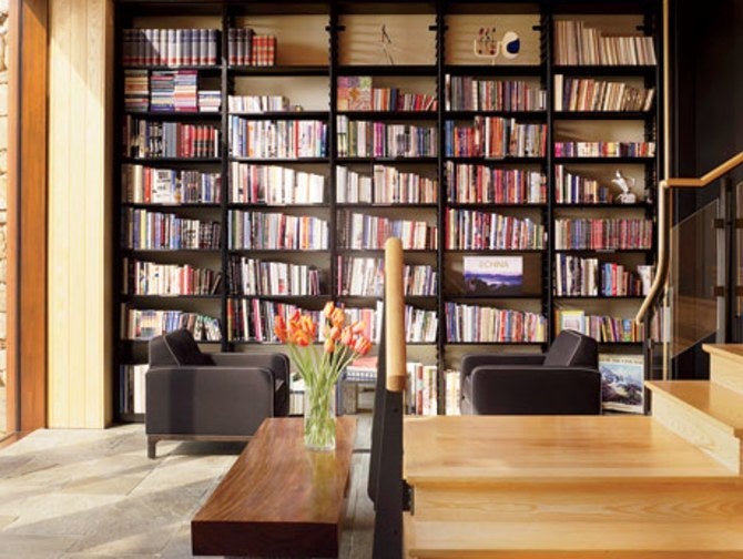 In the lower-level library, custom-made metal shelves hold Abbeville titles; the armchairs are covered in a black wool felt by Donghia.