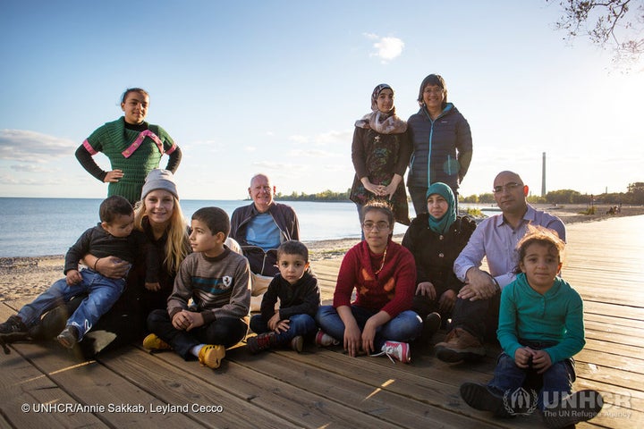 Mohamed Nouman (bottom right) poses with his family and sponsors Thuy Nguyen and Michael Adams on the boardwalk of a Toronto beach.