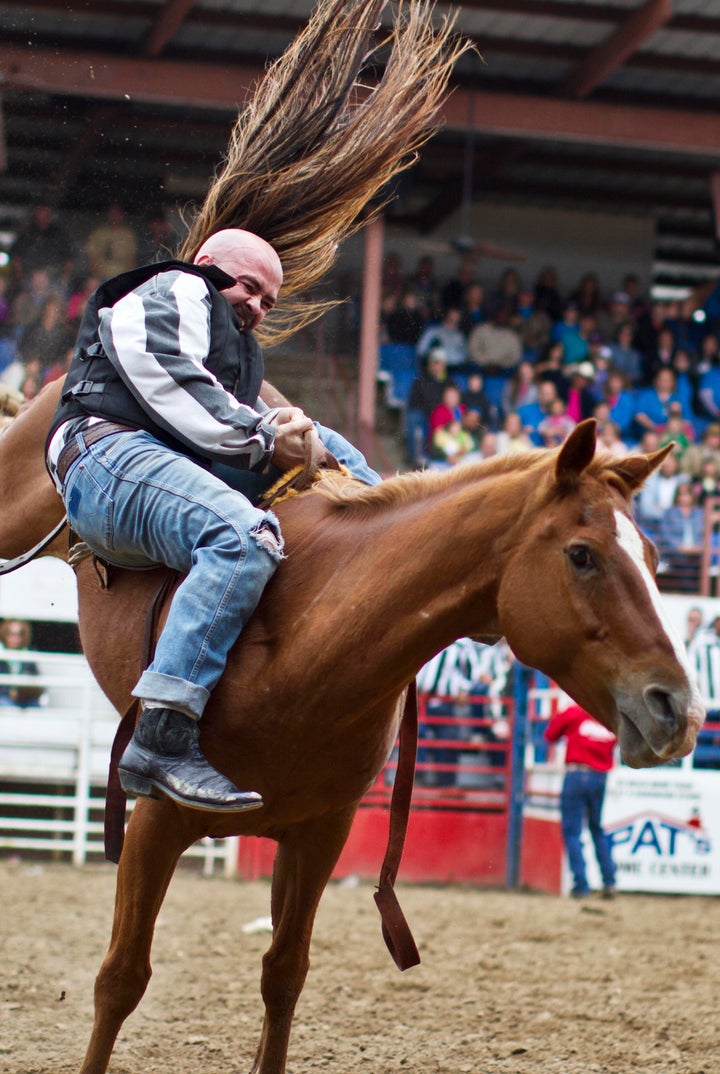 An inmate tries to hold on to a horse during the Angola Rodeo.