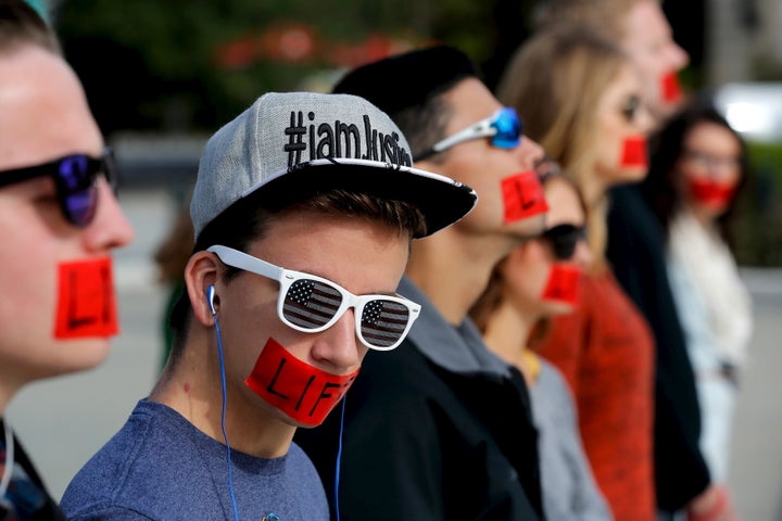 Members of the anti-abortion protest group Bound 4 Life wear red tape over their mouths reading "Life" as they demonstrate at the U.S. Supreme Court building on Oct. 5, 2015.