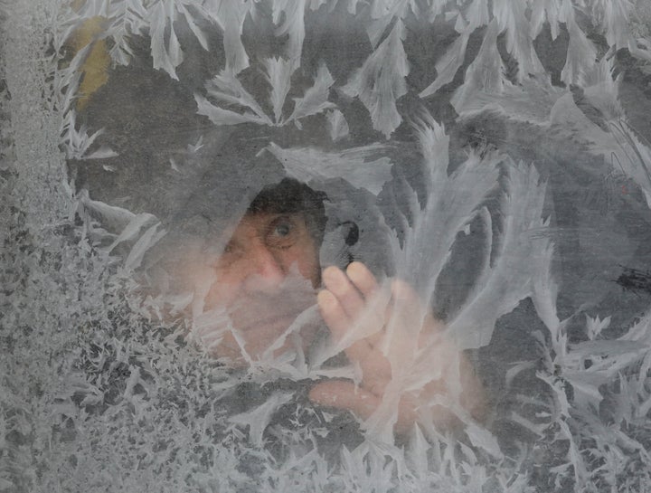 A man looks through a frosted bus window with the air temperature at about minus 16 degrees Celsius (3.2 degrees Fahrenheit),