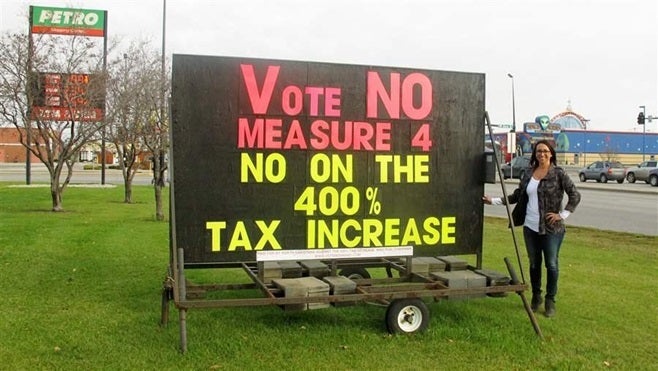 Deanne Schatz poses with a sign she placed in front of her Fargo, North Dakota, truck stop opposing a state tobacco tax incre