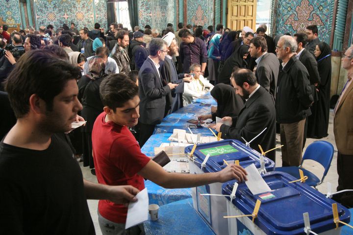 Iranian voters, left, arrive at a polling station to vote for their country's parliamentary and Experts Assembly elections as election staff receive them in Tehran, Iran, Friday, Feb. 26, 2016.