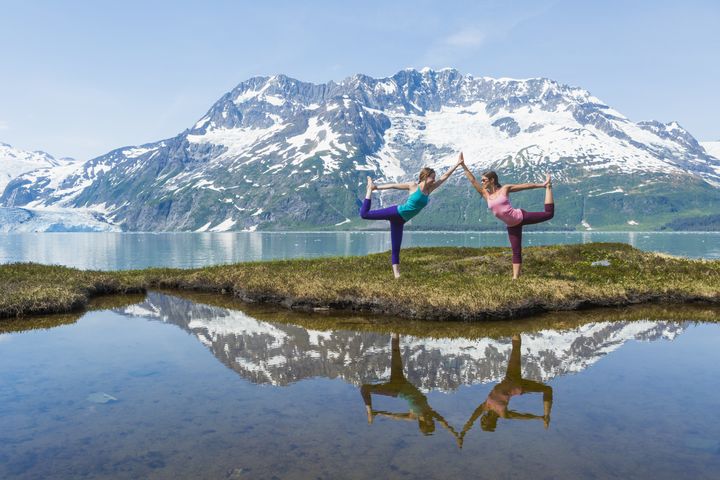 Two young adult women doing yoga with inspirational view of Harriman Fjord, Surprise Glacier, Prince William Sound, Alaska Michael DeYoung via Getty Images
