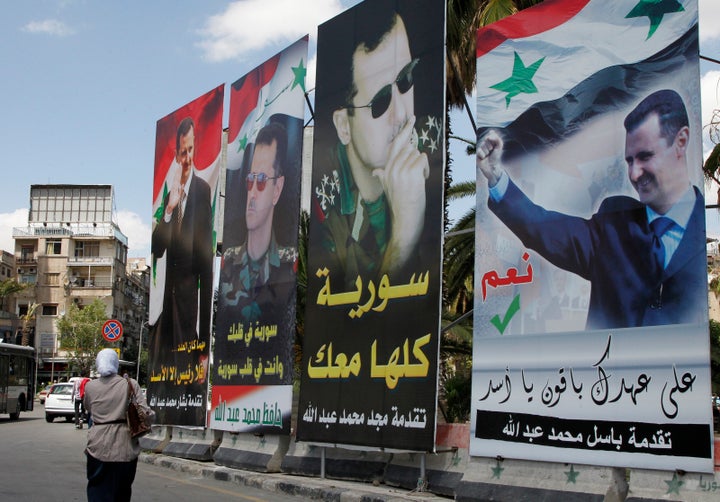 A woman walks past election posters of Syria's President Bashar Assad along a street in Damascus on June 2, 2014.