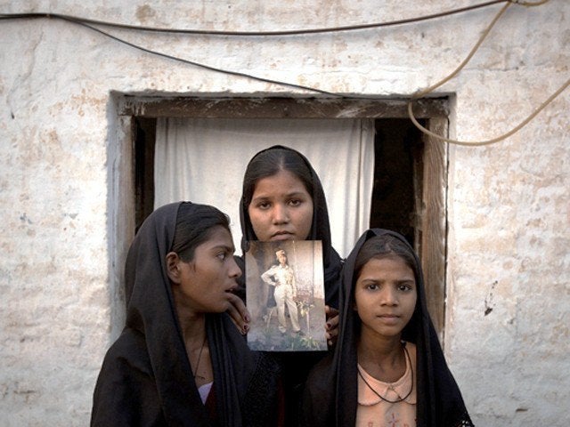 <p>The daughters (now in hiding) of Aasia Bibi with an image of their mother, standing outside their residence.</p>