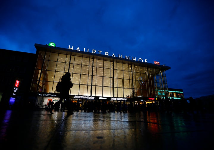 People are silhouetted as they walk past the main railway station in Cologne, Germany, January 5, 2016.