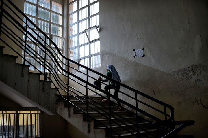 A young Syrian girl climbs the stairs in an abandoned school used by volunteers for hosting families of refugees from Syria and Afghanistan in Athens. 