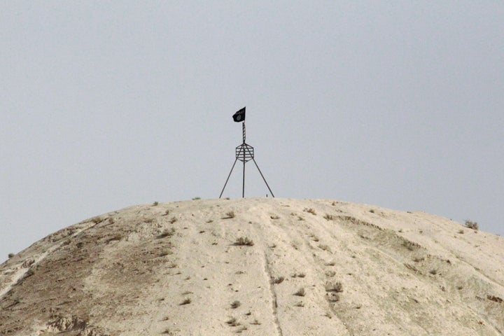 A fluttering Islamic State flag, is flown over a hill in Tel Abyad town on the Syrian-Turkish border.