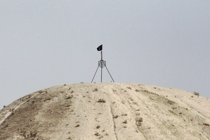 A fluttering Islamic State flag, is flown over a hill in Tel Abyad town on the Syrian-Turkish border. 