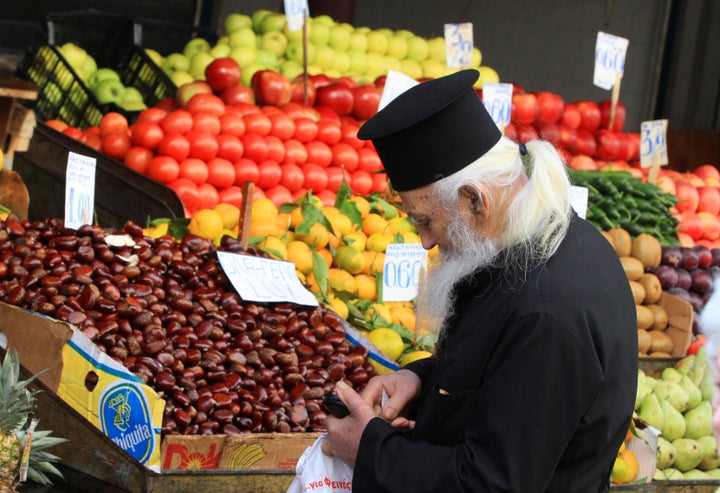 A Greek orthodox priest searches for change to buy vegetables in Athens November 8, 2011.