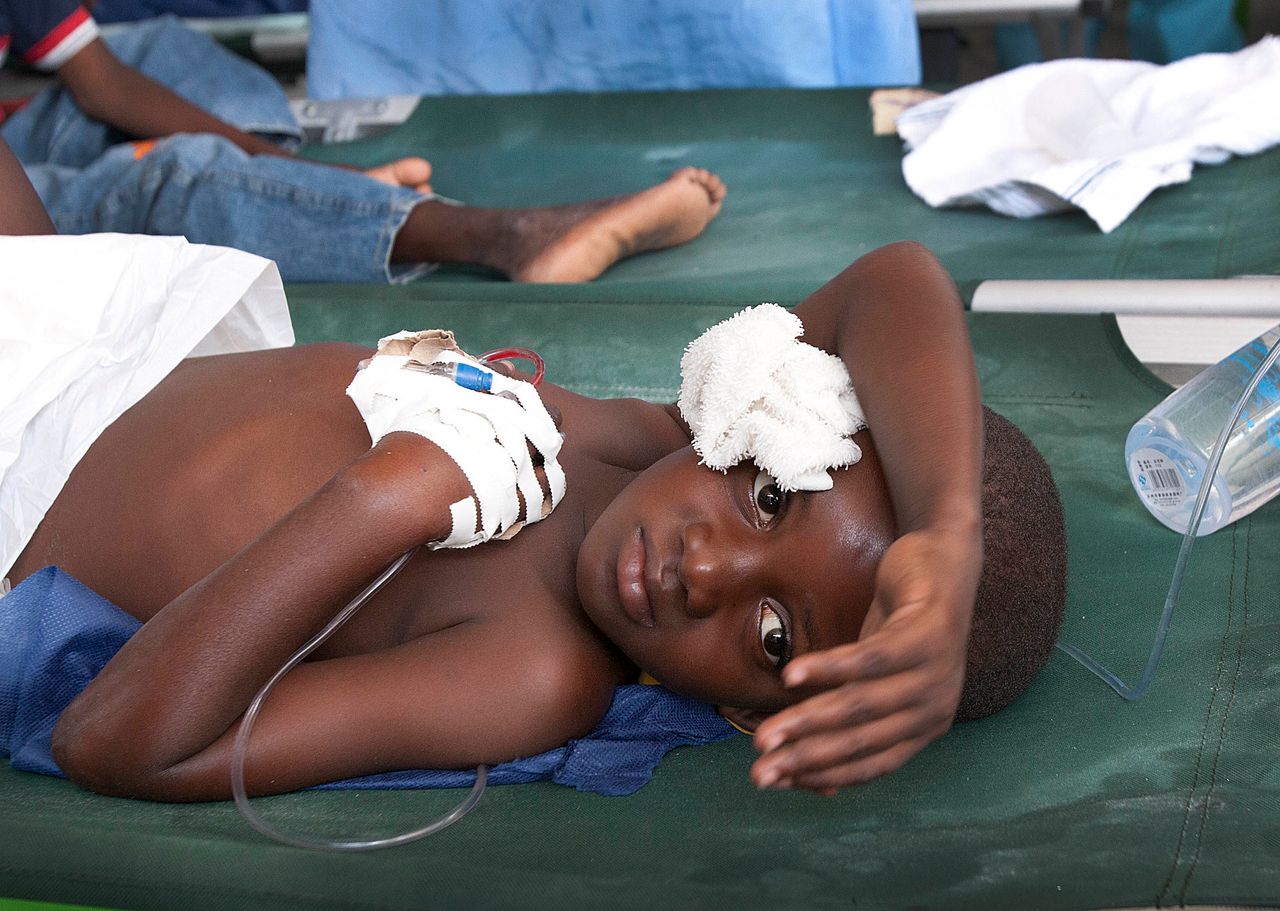 Mackenzy Regis, 7, holds his head while suffering from a case of cholera at the International Red Cross station near Port-au-Prince, Haiti, on Nov. 26, 2010.